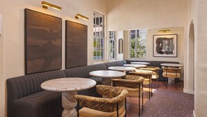 Un espace de détente moderne comprenant un canapé, des tables rondes, des fauteuils à motifs et des œuvres d’art accrochées aux murs.