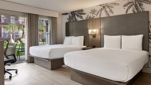 Une chambre d’hôtel avec deux lits, un bureau, une chaise et une vue sur un balcon agrémenté de palmiers.