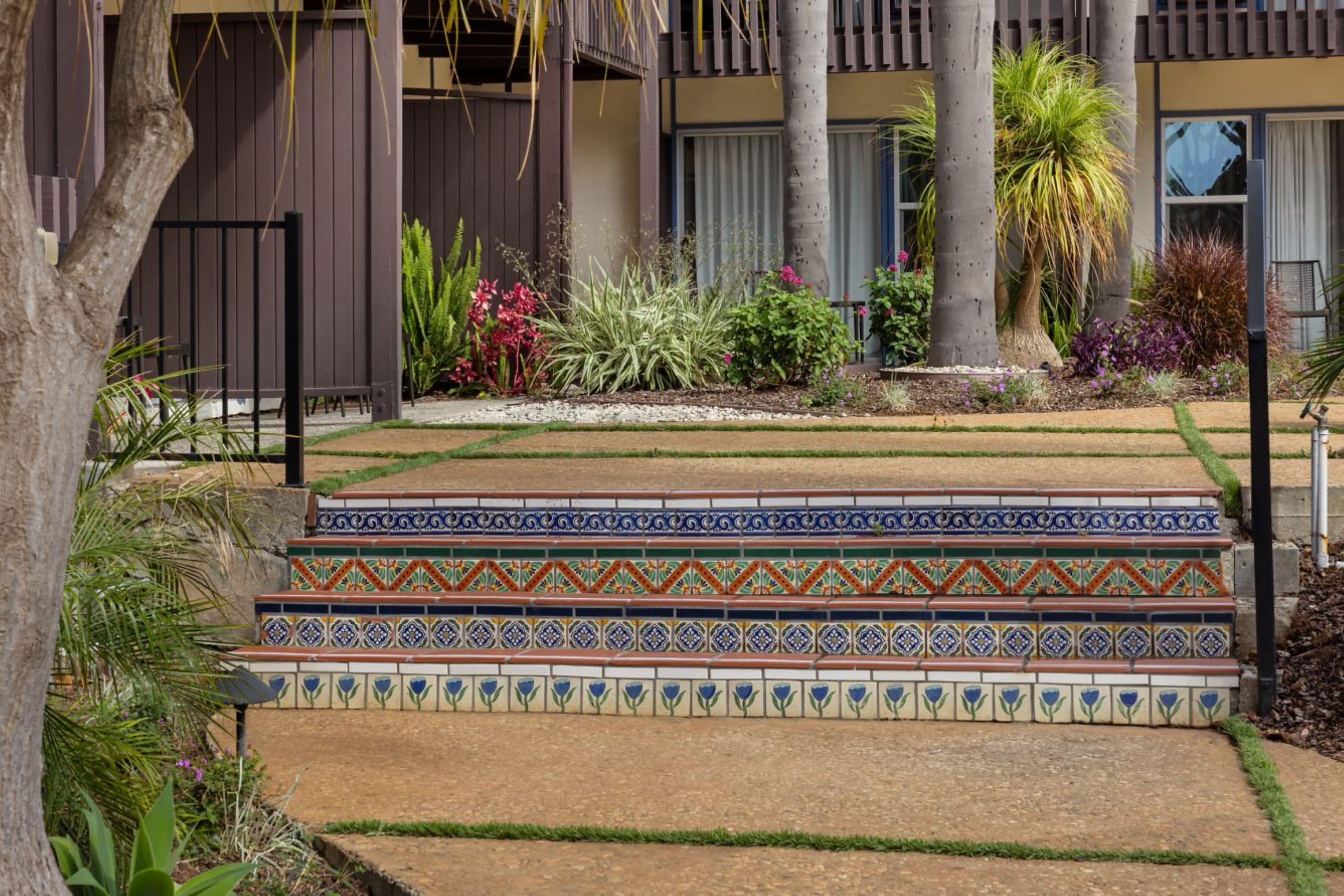 A garden with steps leading to a building, surrounded by various plants and trees.