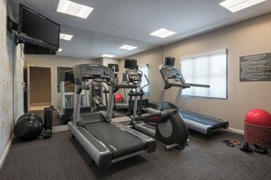 A fitness room with treadmills, elliptical machines, and exercise balls.