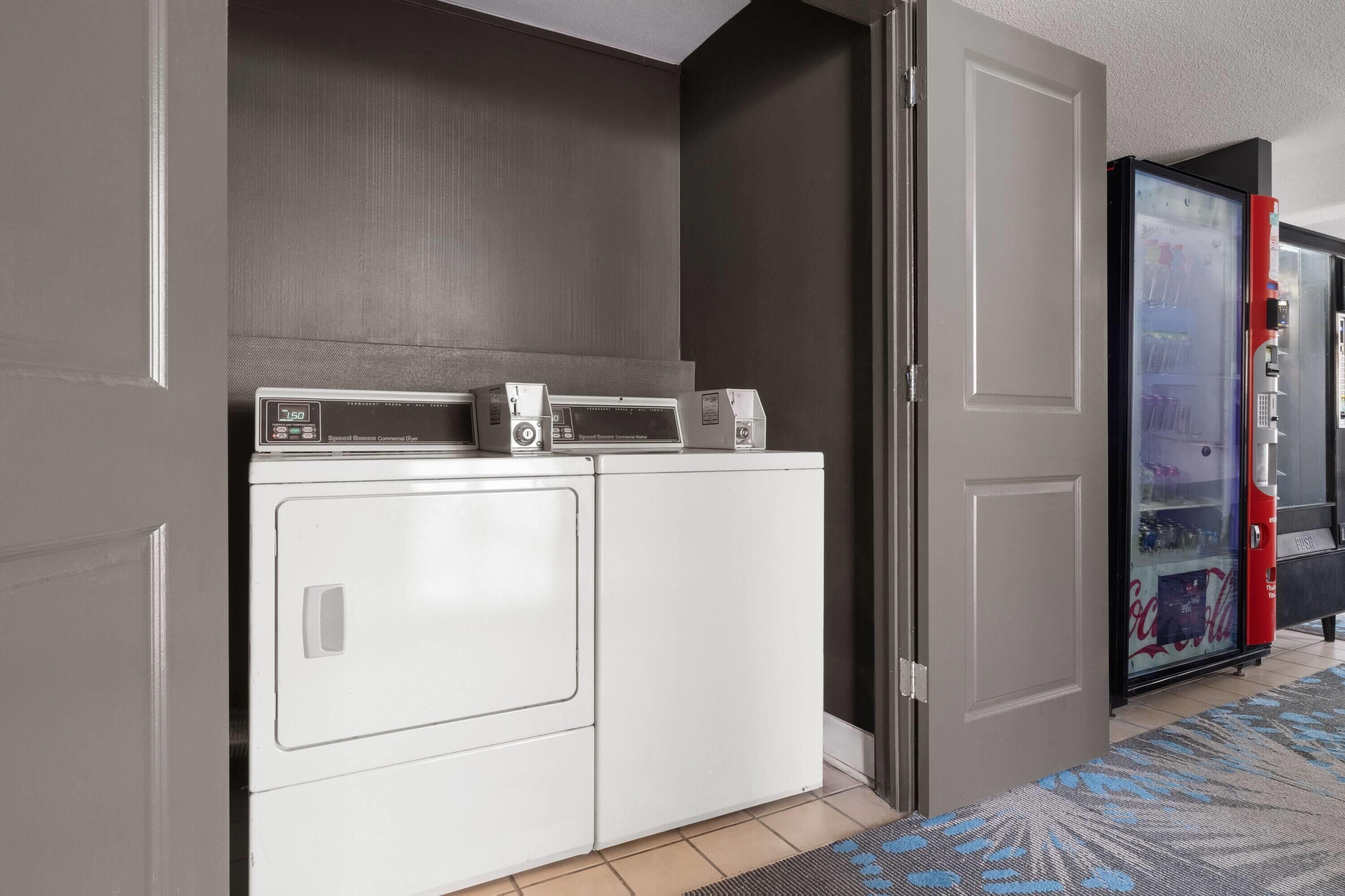 A laundry area with a washing machine and dryer, a microwave, and a refrigerator.