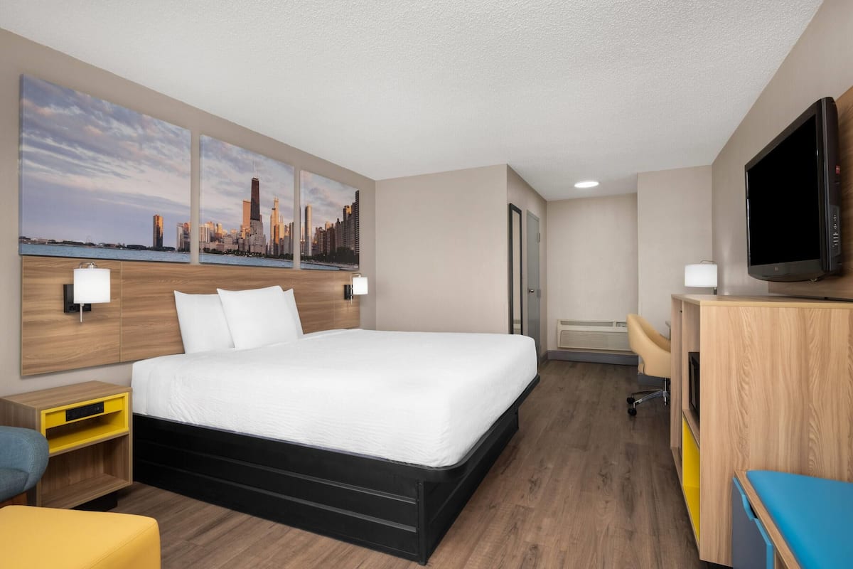 A hotel room with a bed, a TV, a desk, and a cityscape view.