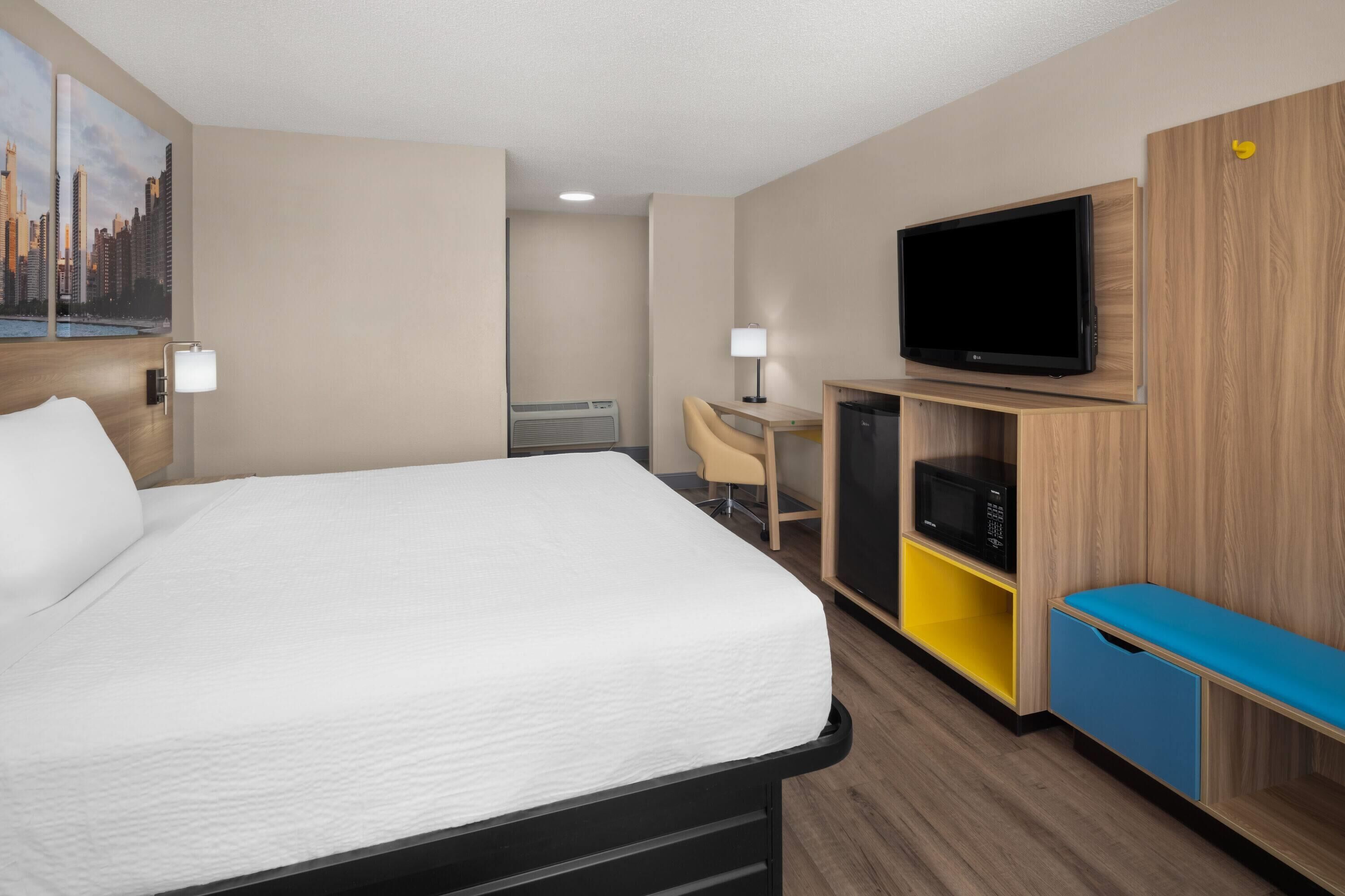 Ein Hotelzimmer mit Bett, Schreibtisch, Fernseher und Mikrowelle.
