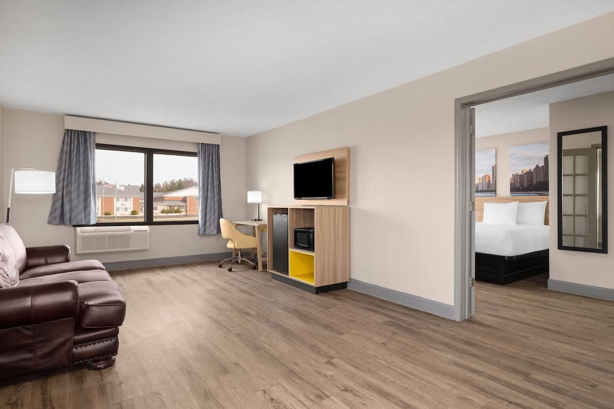 A hotel room with a bed, a desk, a TV, a couch, and a view of the city.