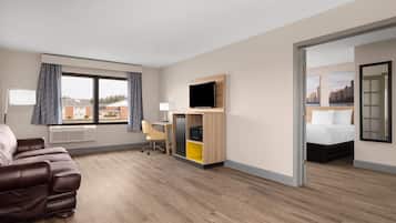 Una camera d'albergo con un letto, una scrivania, una TV, un divano e vista sulla città.