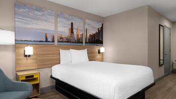 A hotel room with a large bed, a desk, a chair, a nightstand, and two wall-mounted lamps.