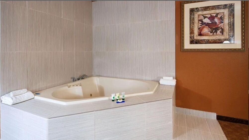 Un baño moderno con una bañera independiente, un perchero y una obra de arte enmarcada en la pared.