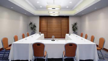 A conference room with a long table, chairs, and a wooden door in the background.