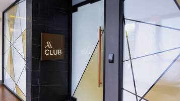 A modern interior with a black marble wall, a glass door with a wooden handle, and a sign that reads "CLUB".