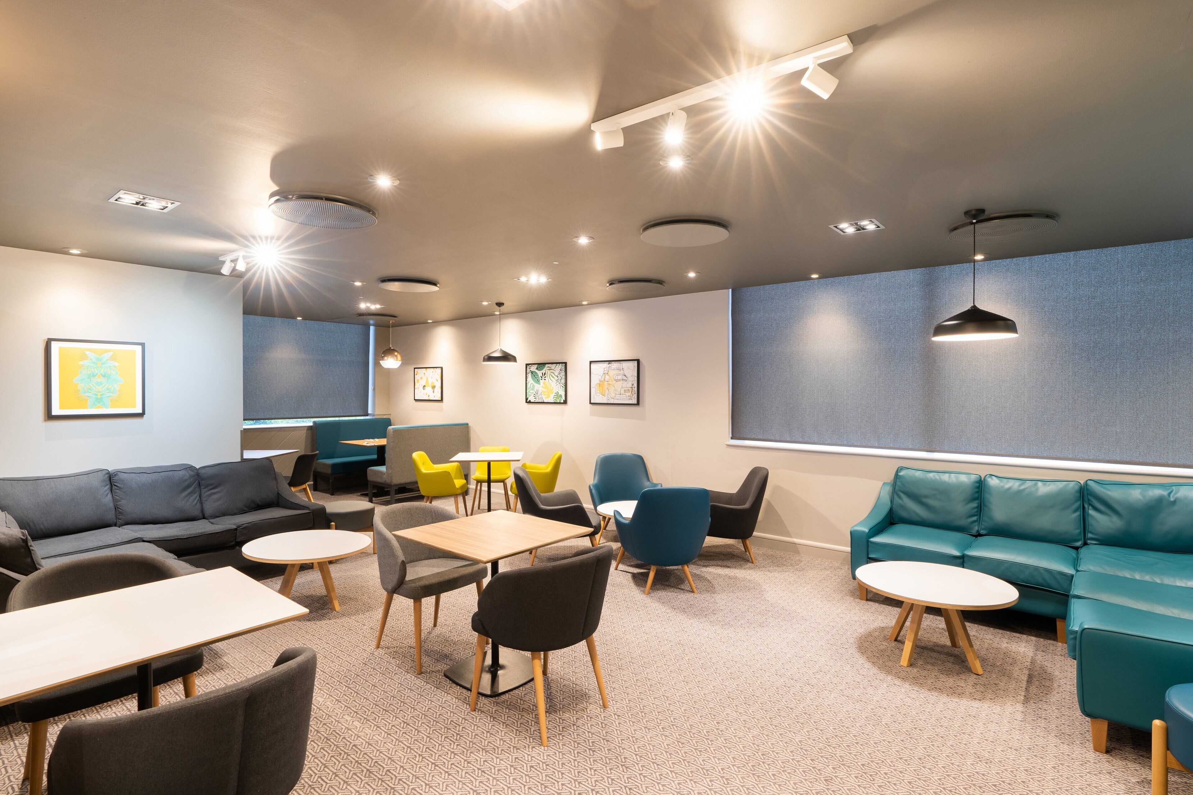 A modern lounge area with seating arrangements, tables, and artwork on the walls.