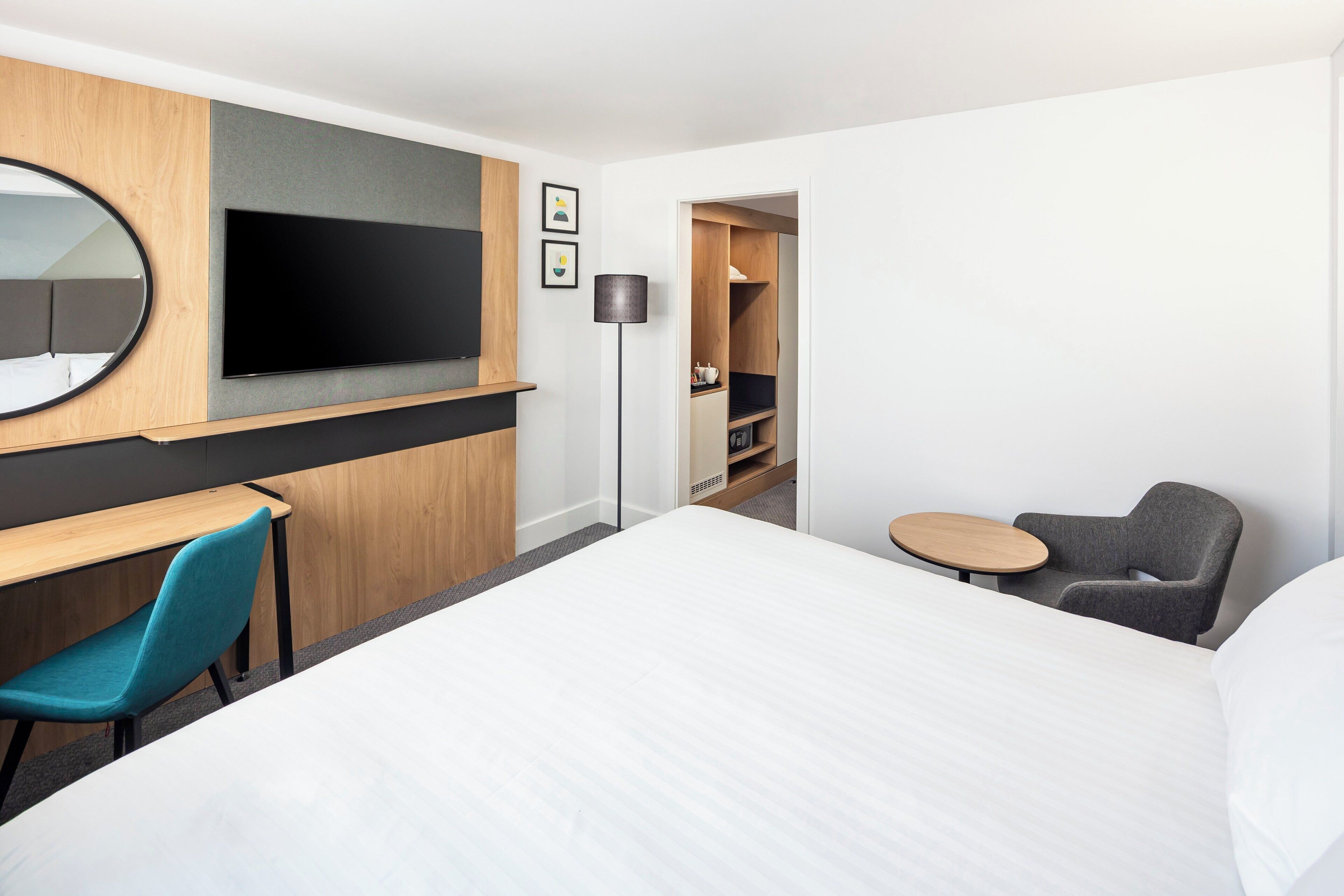 Una habitación de hotel con cama, escritorio, silla, televisor y una mesita.