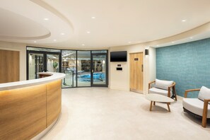 Un espace d’accueil doté d’un comptoir incurvé, de sièges, d’une piscine et d’un téléviseur.