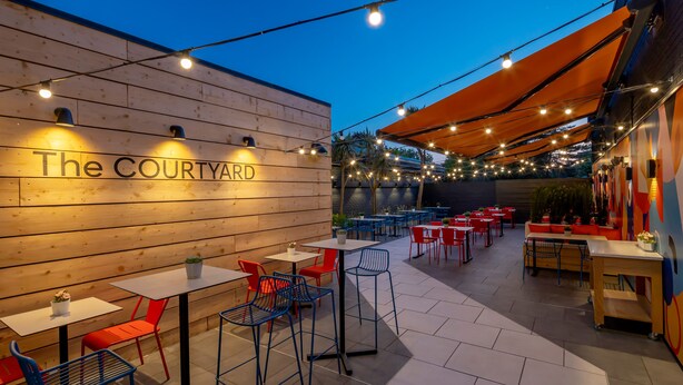 An outdoor seating area with tables and chairs, a wooden wall with the text "The COURTYARD," and string lights. - Holiday Inn Southampton-Eastleigh M3, jct13 by IHG (Eastleigh)