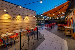 An outdoor seating area with tables and chairs, a wooden wall with the text "The COURTYARD," and string lights. - Holiday Inn Southampton-Eastleigh M3, jct13 by IHG (Eastleigh)