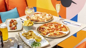 A dining table with various food items including pizza, fries, and a salad, along with drinks and cutlery. - Holiday Inn Southampton-Eastleigh M3, jct13 by IHG (Eastleigh)