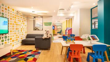 Children can play and learn in this vibrant playroom with a colorful rug, sofa, and chairs.