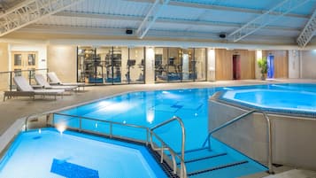 An indoor swimming pool with multiple lanes, exercise equipment, and lounge areas.