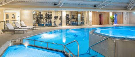 An indoor swimming pool with multiple lanes, exercise equipment, and lounge areas.