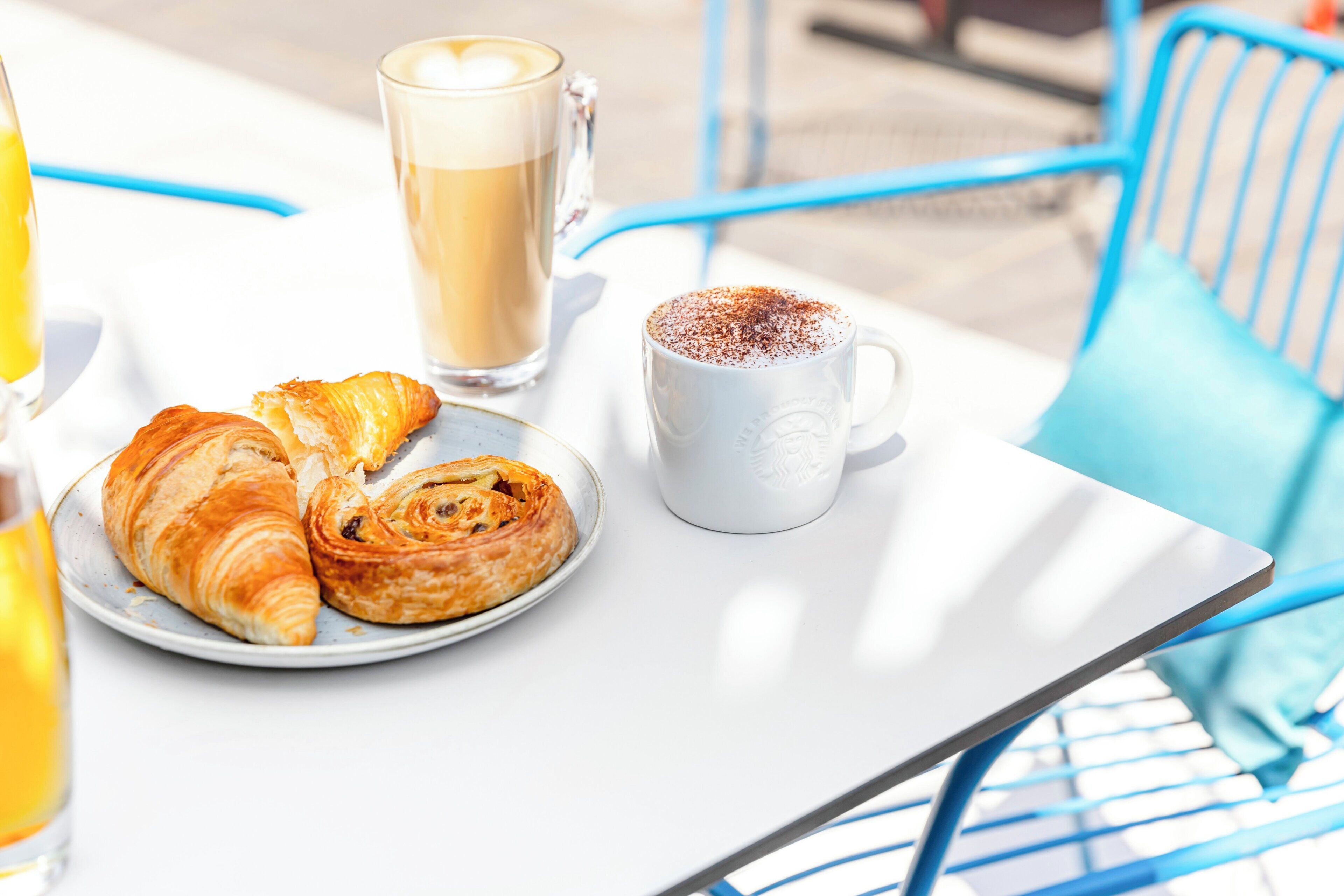 A table with croissants, a coffee mug, and a glass of coffee.