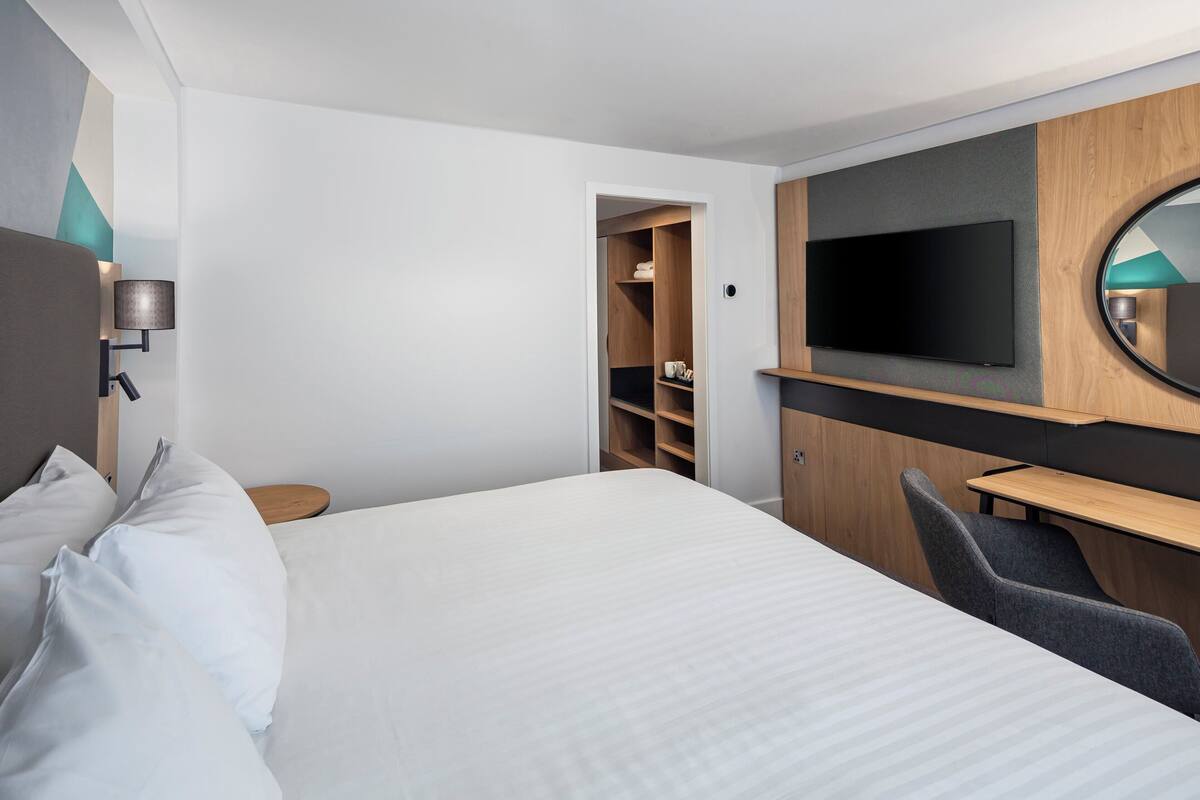 Ett hotellrum med en säng, ett skrivbord, en tv och en garderob.