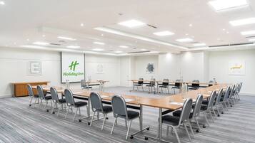 A conference room with a long table, chairs, and a Holiday Inn sign on the wall.