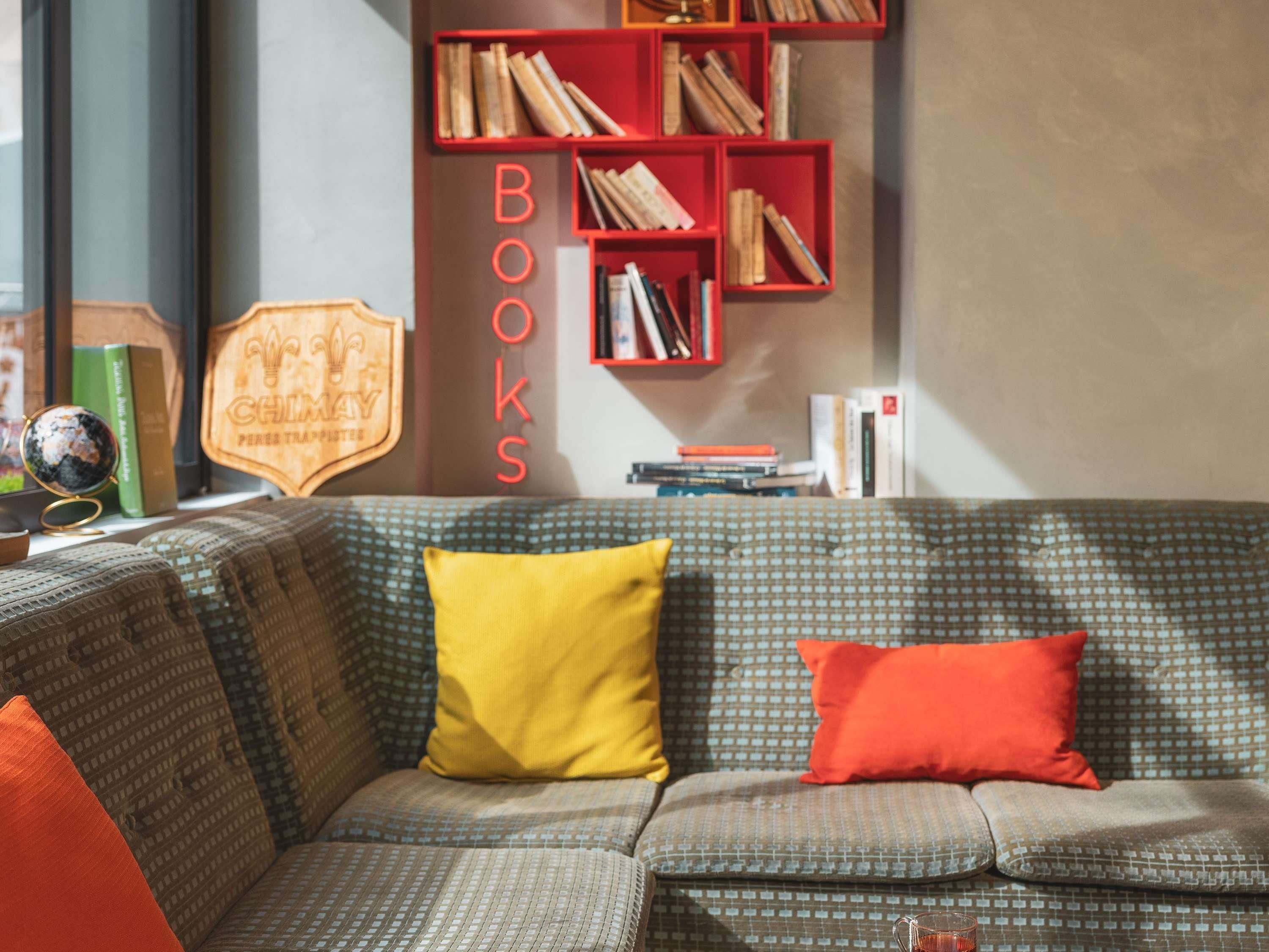 Een gezellige leeshoek met een gestreept bankje, een boekenplank vol boeken en een wereldbol op een bijzettafeltje.