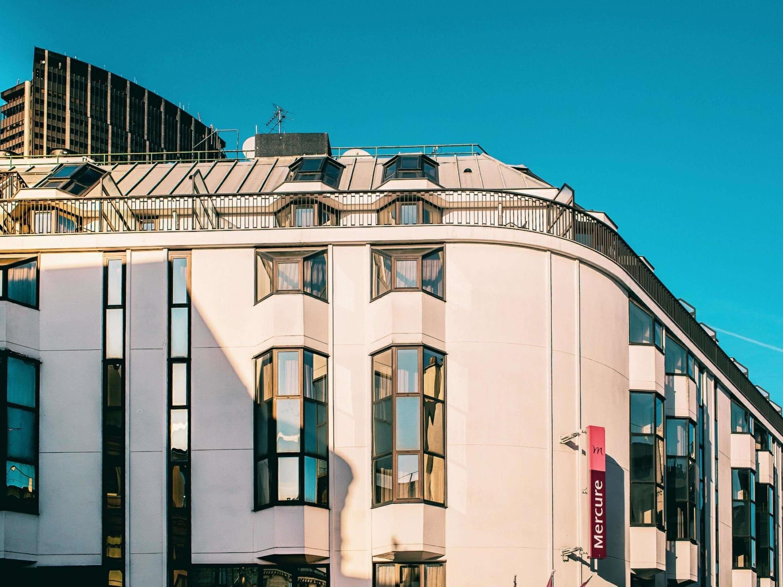 A modern building with a curved facade, large windows, and a visible Mercure hotel sign.
