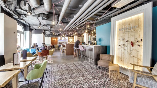 A modern interior with exposed ductwork, a patterned floor, and a bar area.
