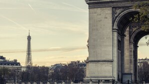 The Arc de Triomphe in Paris, with the Eiffel Tower in the background.