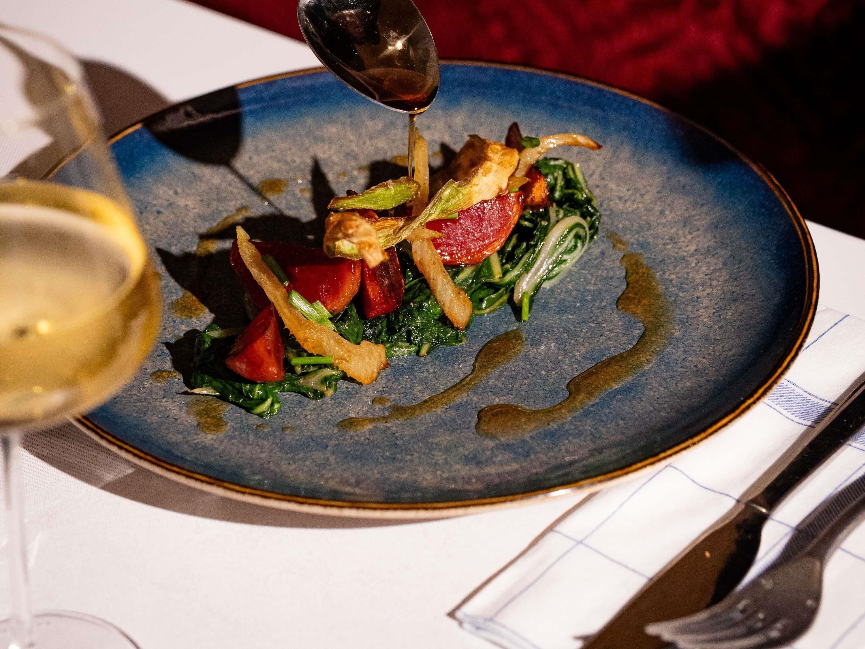 A plate of food with a spoonful of sauce being poured onto it.