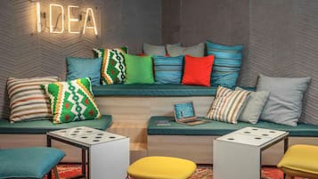 A modern lounge area with a sofa set, a neon sign, and a dice table.