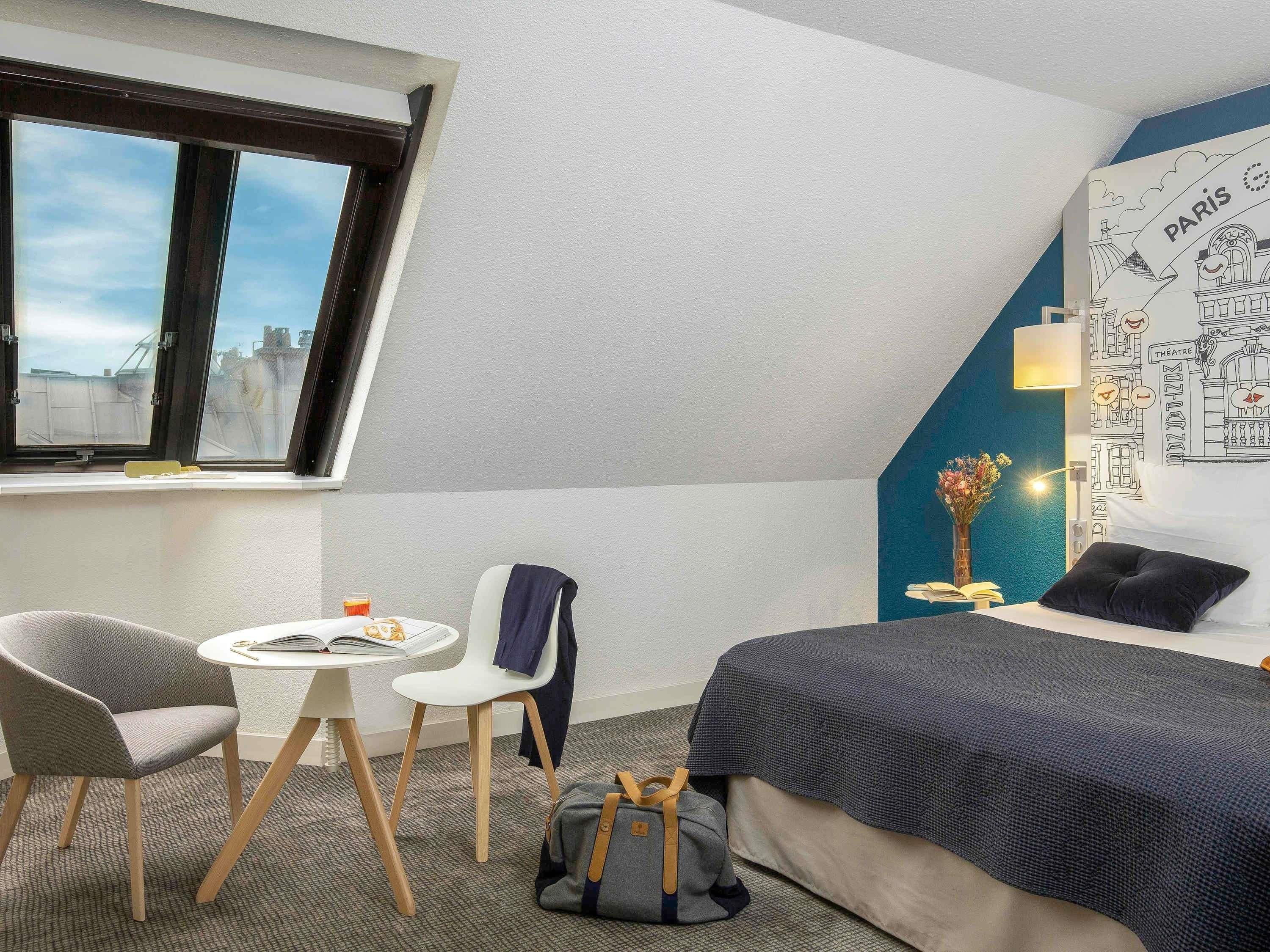 Hotelkamer met een bed, een bureau met stoel, een raam en een muur met een kaart.