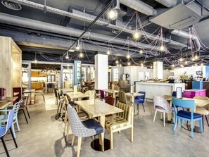 A modern cafe interior with tables, chairs, and hanging lights.
