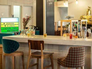 A bar area with a counter, bar stools, and a variety of bottles and glasses. - Mercure Paris Centre Gare Montparnasse (Paris)