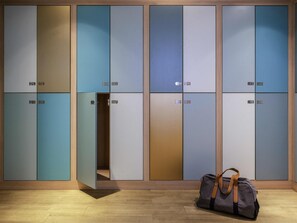 A row of lockers with numbers on them, a bag on the floor, and wooden paneling on the walls. - Mercure Paris Centre Gare Montparnasse (Paris)