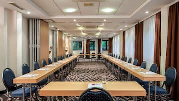 A conference room with a long table, chairs, and a carpeted floor.