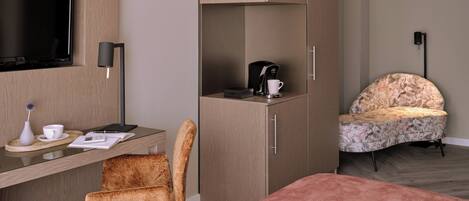 A hotel room with a bed, a desk with a chair, a television, a coffee maker, and a decorative chair.