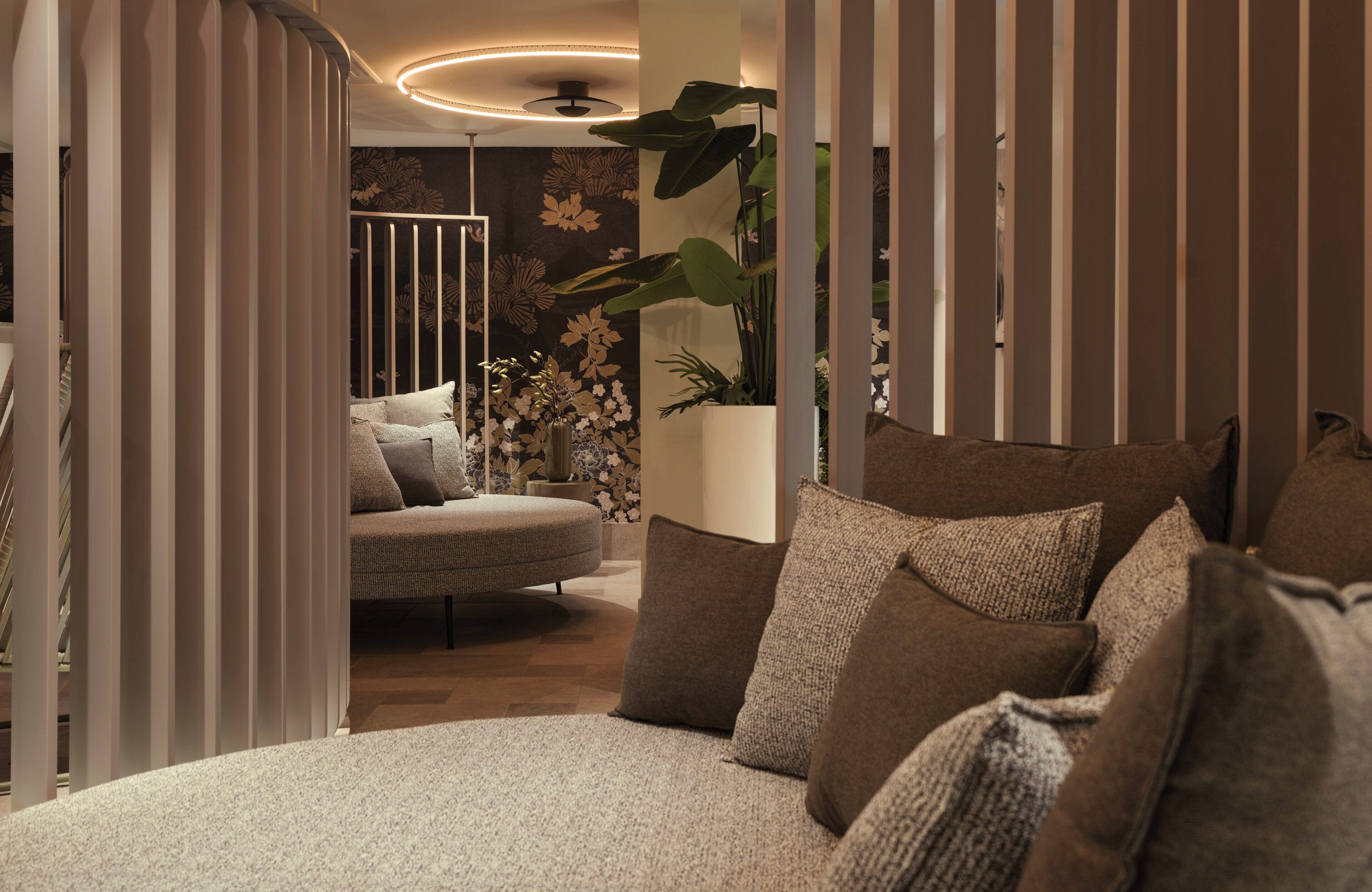 A modern bedroom with a round bed, striped curtains, and a large potted plant.