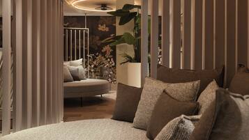 A modern bedroom with a round bed, striped curtains, and a large potted plant.