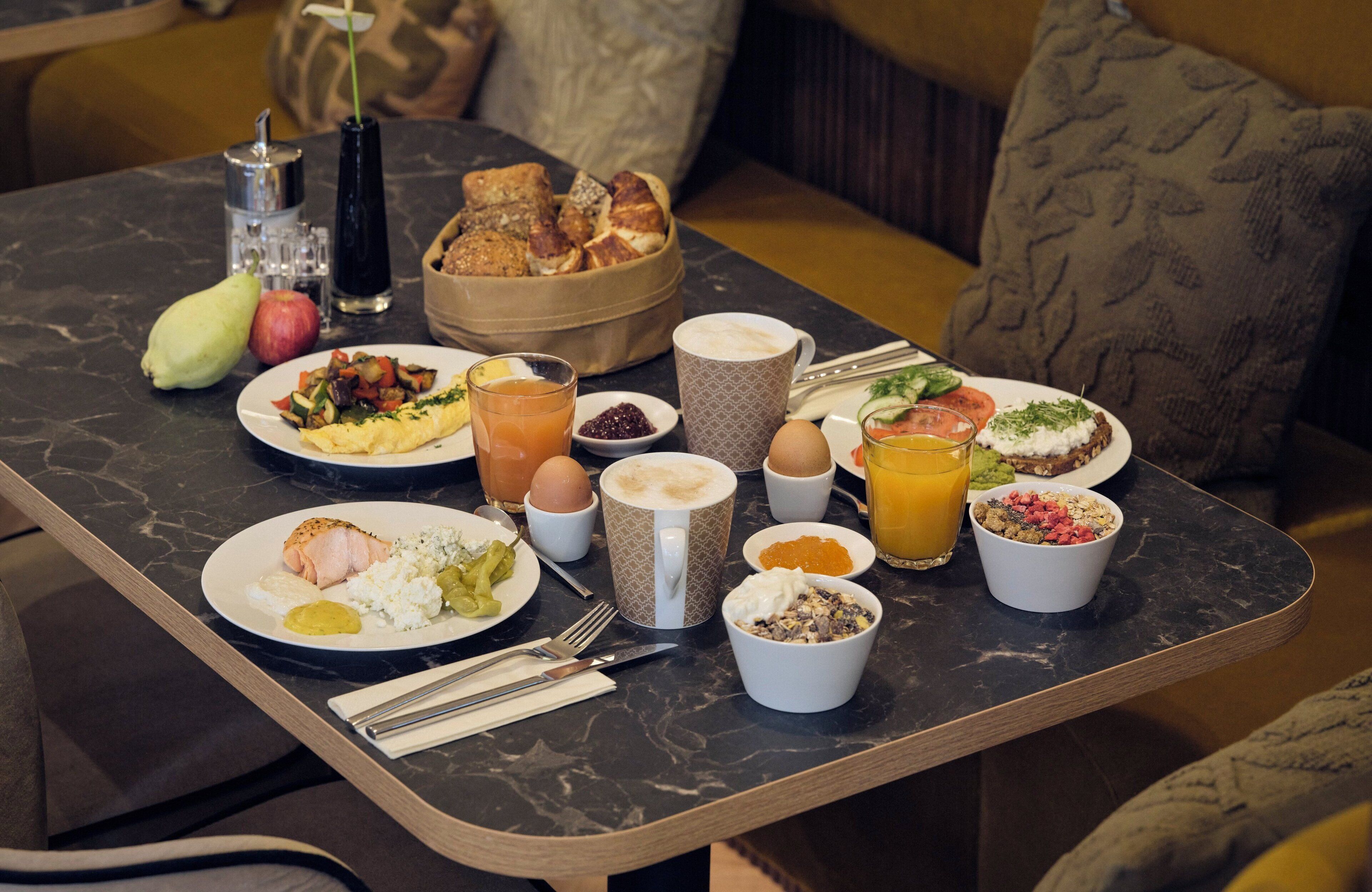 Una mesa de desayuno con diferentes platos, como huevos, tostadas y fruta.