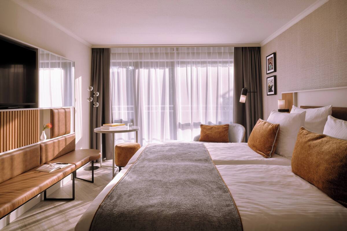 Une chambre d’hôtel avec un grand lit, un canapé, une petite table et un téléviseur.