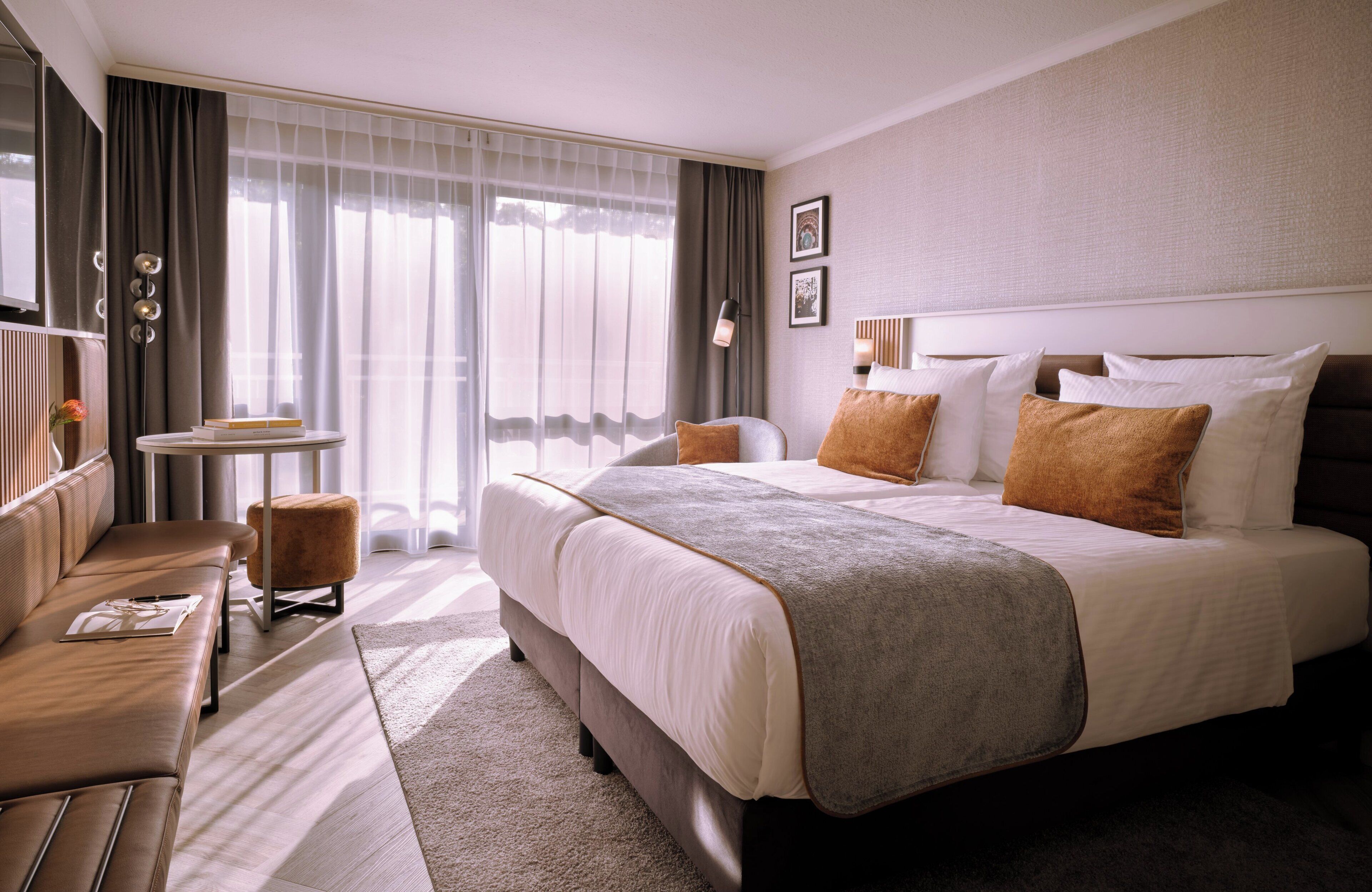 Una habitación de hotel con una cama grande, un sofá, una mesita y una silla.