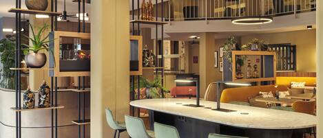 A modern kitchen with a central island, bar stools, and a mezzanine level with seating.