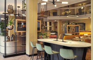 Uma cozinha moderna com ilha central, banquetas e um mezanino com assentos.