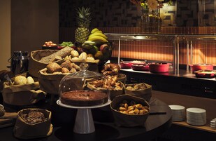 Um buffet com diversos produtos de pastelaria, frutas e um bolo à mostra.