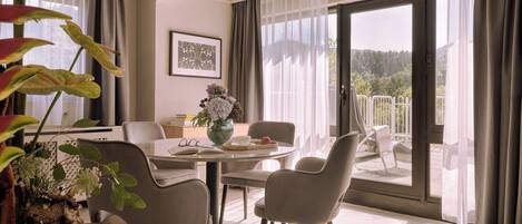 A modern living room with a dining area, large windows, and a view of the outdoors.
