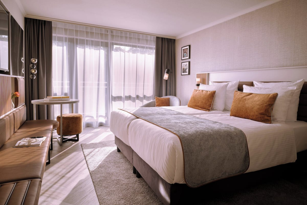 Une chambre d’hôtel avec un grand lit, un canapé, une petite table et une chaise.