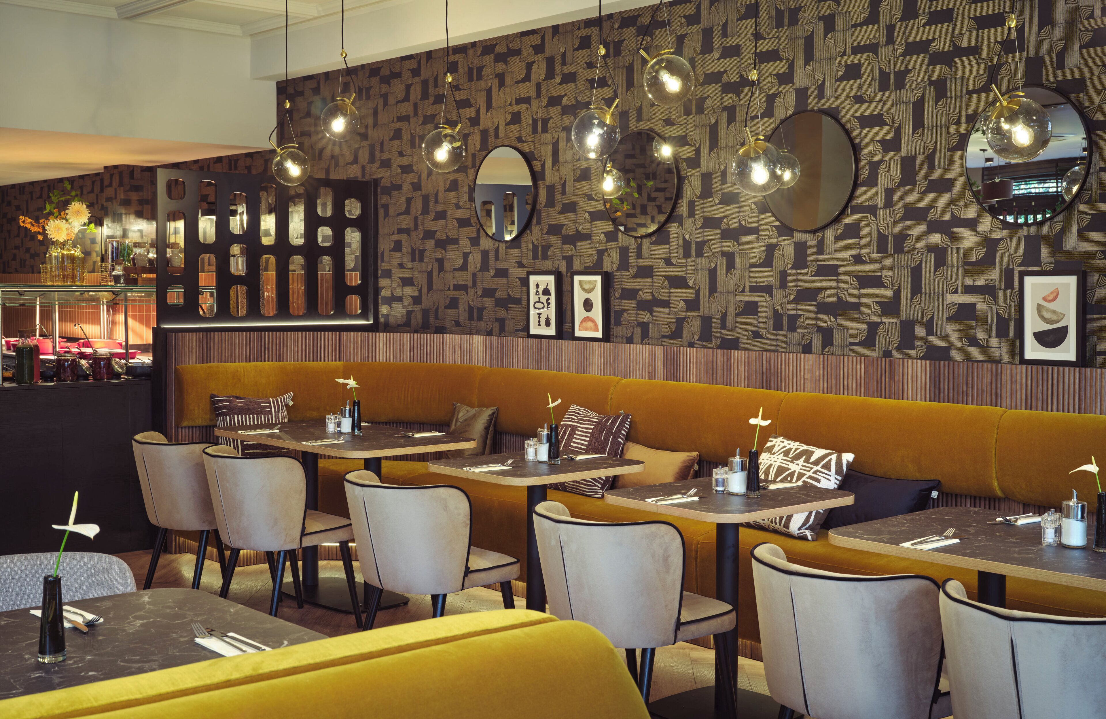 Ein Restaurantinneres mit Sitzgelegenheiten in Form von Boxen, Tischen und hängenden Pendelleuchten.