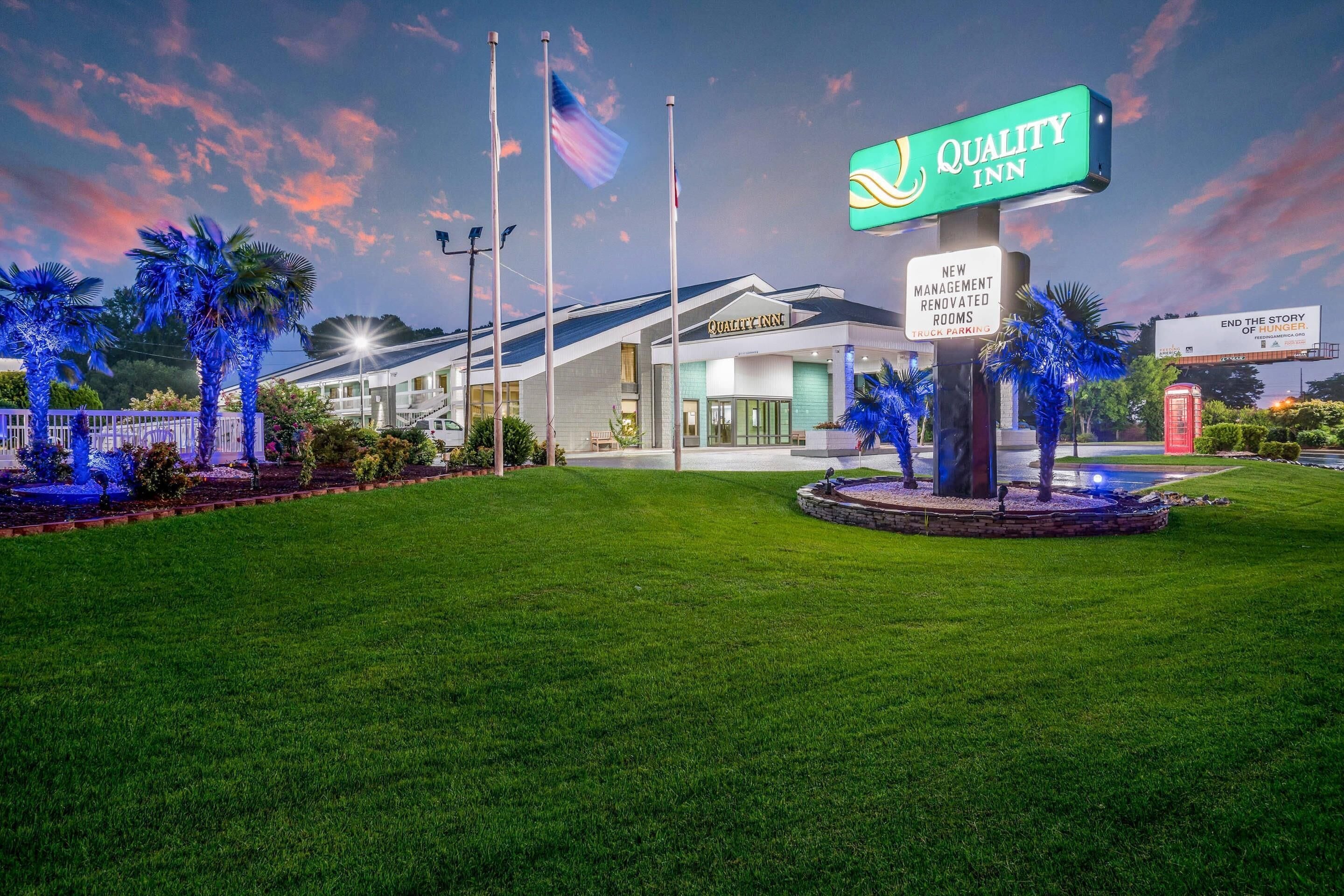 A Quality Inn hotel with a sign indicating new management and renovated rooms.