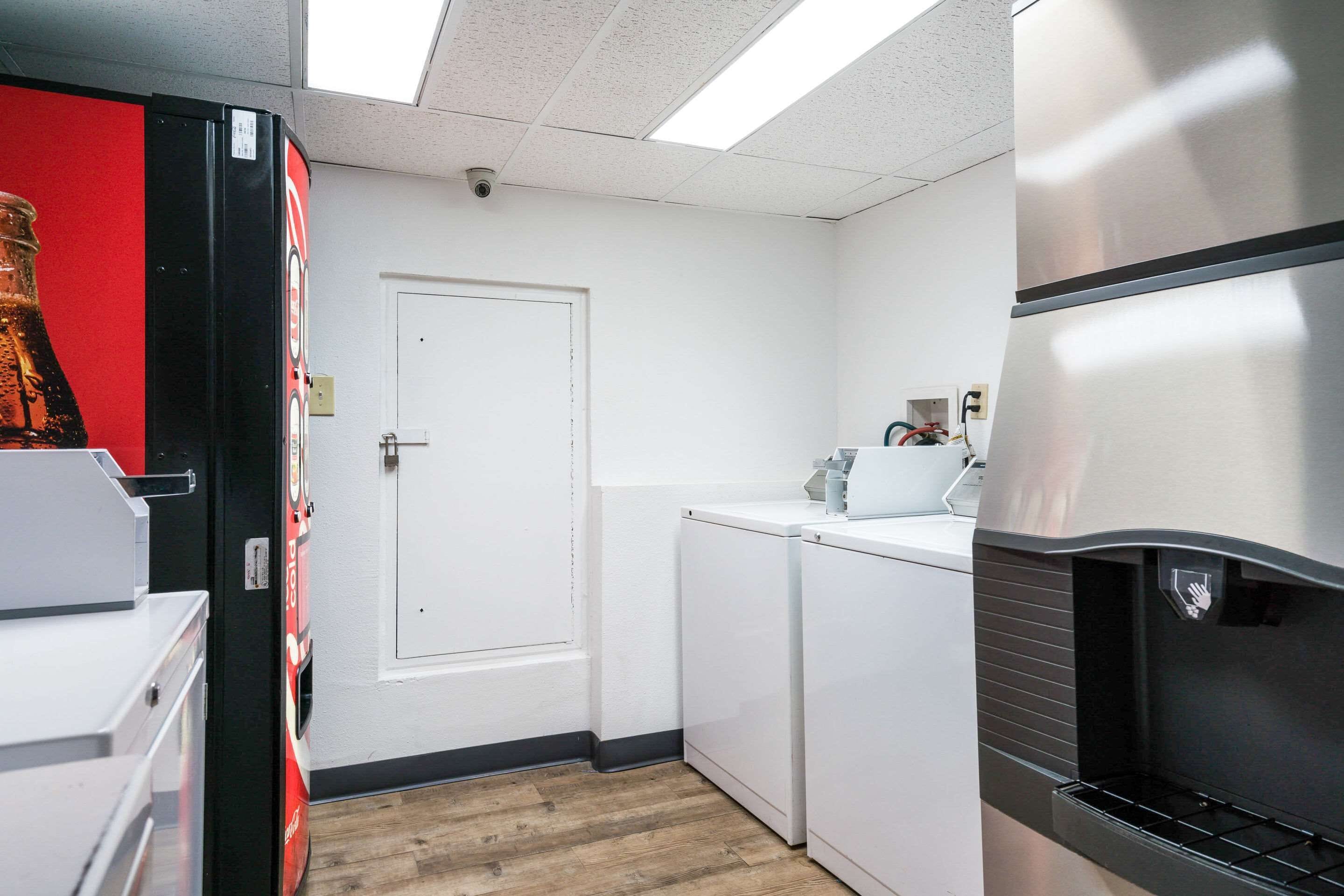 A compact kitchen with a refrigerator, a washing machine, and a coffee machine.